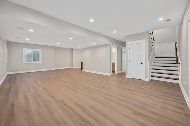 below grade area with recessed lighting, stairway, and light wood finished floors