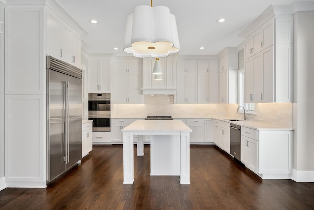 kitchen featuring a sink, appliances with stainless steel finishes, light countertops, and white cabinetry