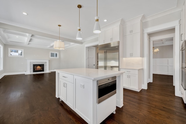 kitchen with coffered ceiling, a fireplace with flush hearth, stainless steel built in fridge, beamed ceiling, and open floor plan