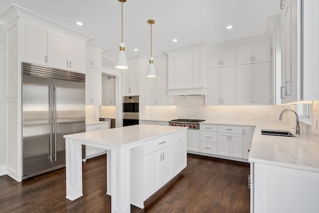 kitchen featuring a kitchen island, dark wood-style flooring, a sink, stainless steel appliances, and tasteful backsplash