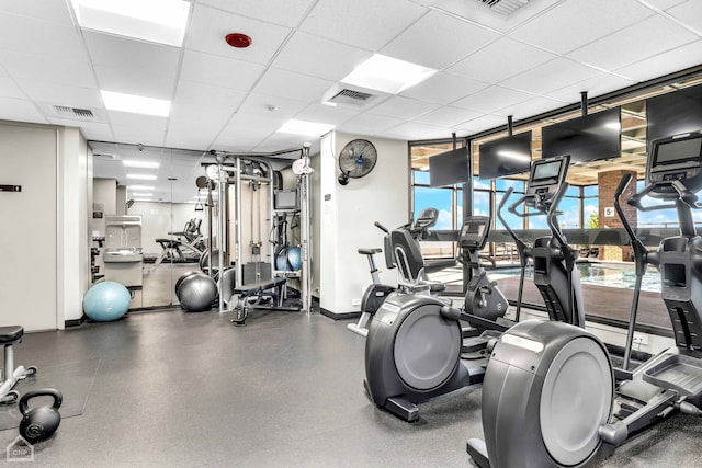 exercise room featuring visible vents, a paneled ceiling, baseboards, and floor to ceiling windows