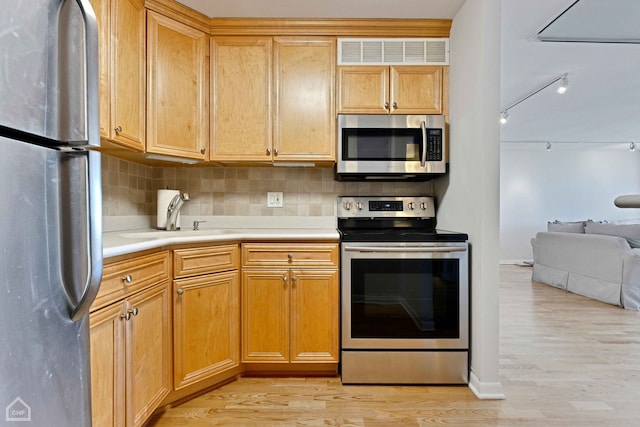 kitchen with tasteful backsplash, visible vents, light wood-type flooring, stainless steel appliances, and a sink