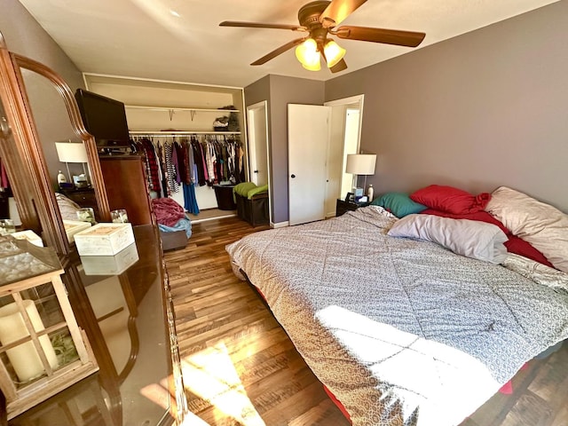 bedroom with a ceiling fan, wood finished floors, and a closet