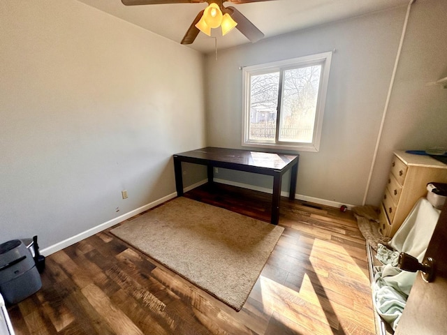 unfurnished office with a ceiling fan, baseboards, and wood finished floors