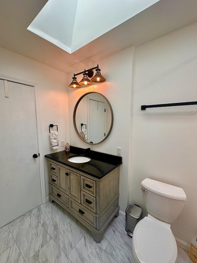 half bath with toilet, marble finish floor, and vanity