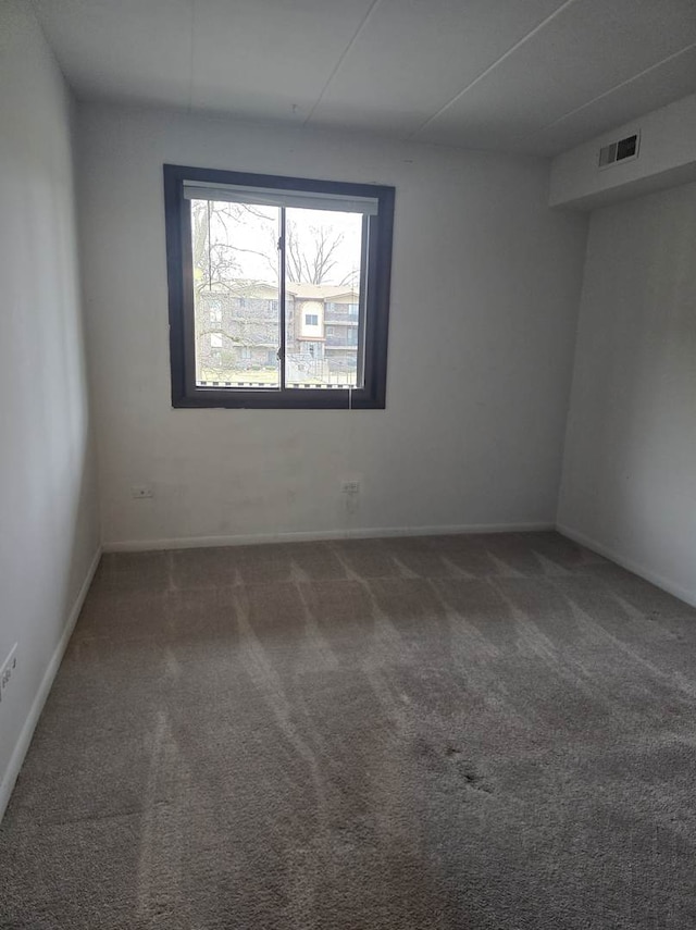 spare room with carpet flooring, baseboards, and visible vents