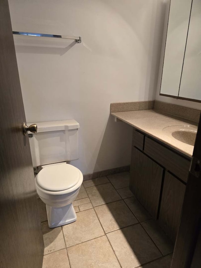 bathroom with vanity, toilet, baseboards, and tile patterned flooring