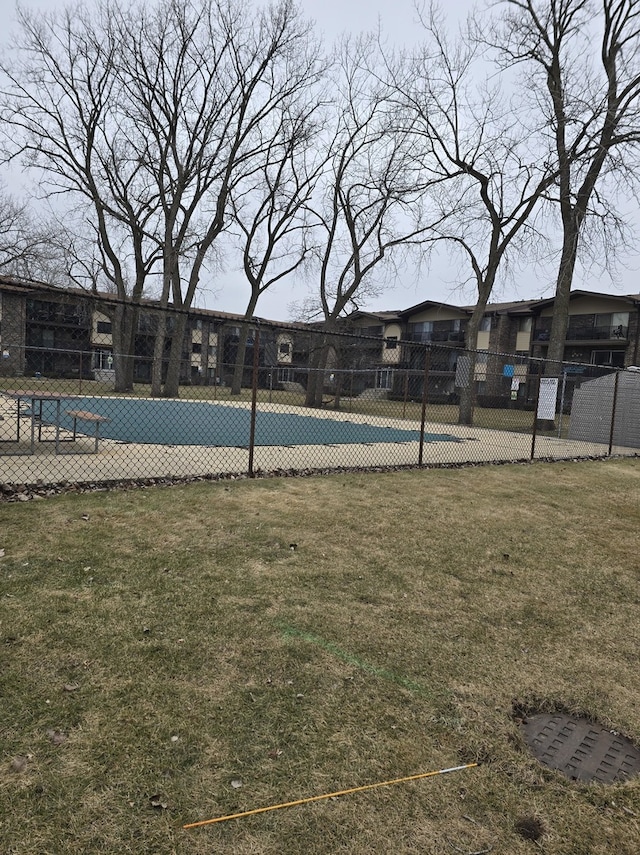 view of swimming pool featuring a yard and fence