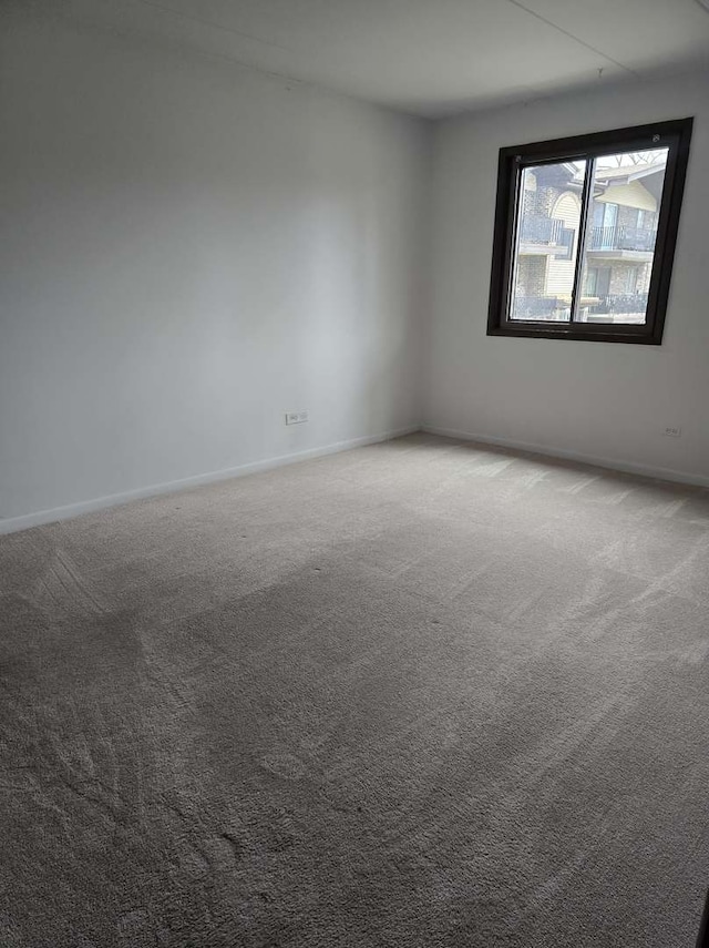 unfurnished room with carpet and baseboards