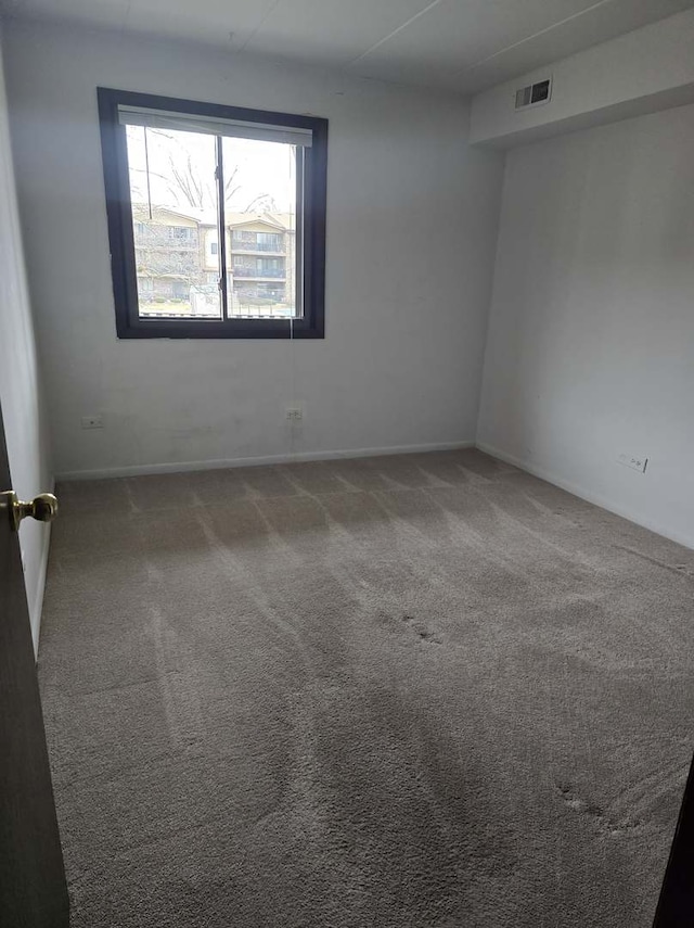 empty room with visible vents, baseboards, and carpet