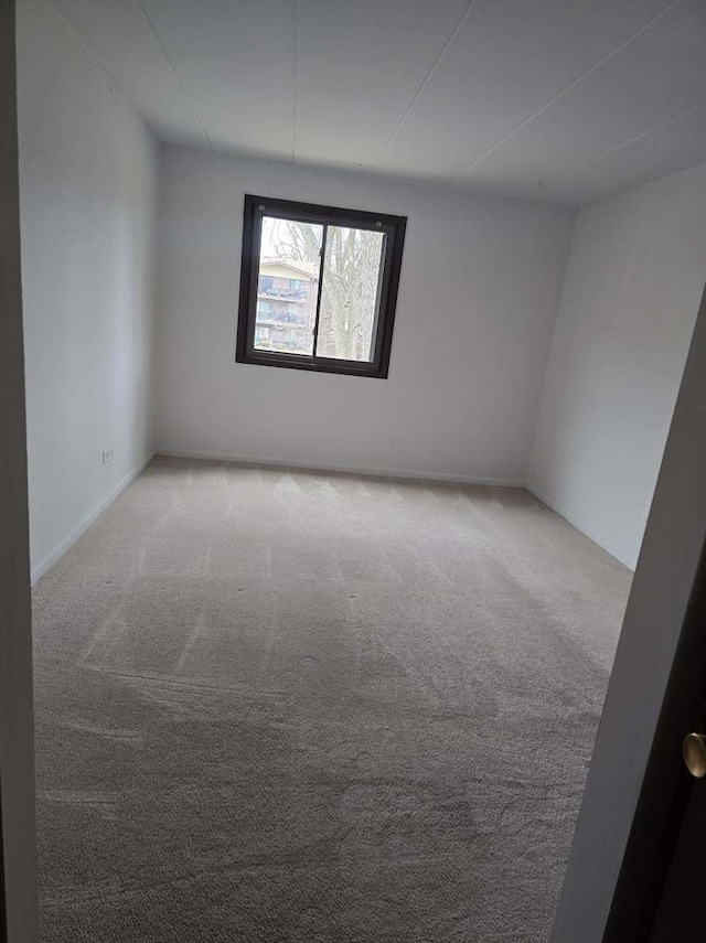 spare room featuring carpet and baseboards