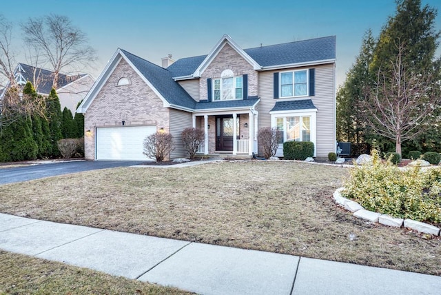 view of front of property with a front lawn, driveway, an attached garage, brick siding, and a chimney