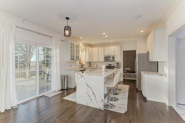 kitchen with visible vents, a kitchen island, light stone counters, white cabinets, and stainless steel appliances