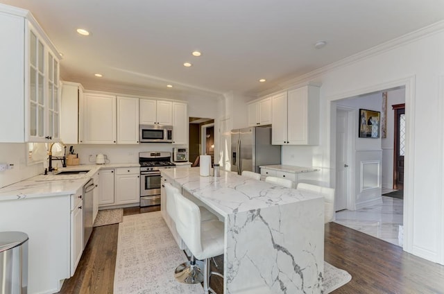 kitchen featuring a kitchen island, recessed lighting, white cabinets, stainless steel appliances, and a sink