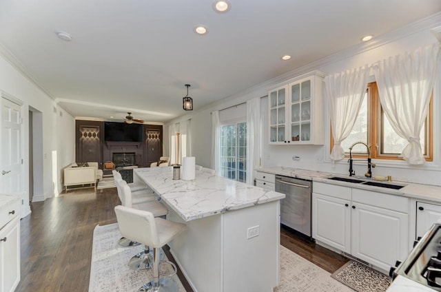 kitchen with a sink, stainless steel dishwasher, open floor plan, white cabinets, and a fireplace