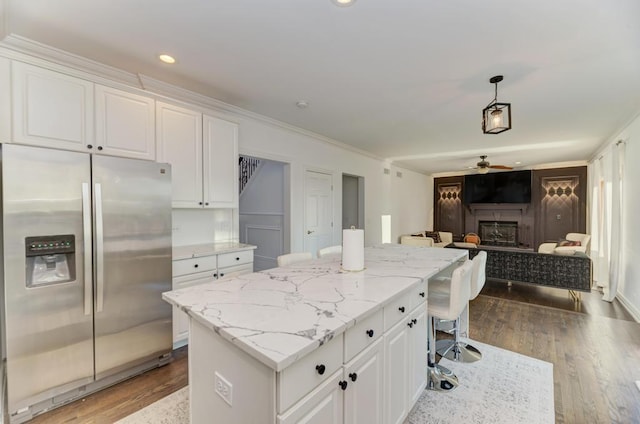 kitchen with wood finished floors, open floor plan, a fireplace, and stainless steel fridge