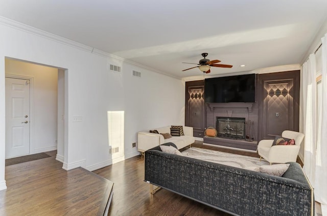 living area with visible vents, a fireplace with raised hearth, baseboards, and wood finished floors