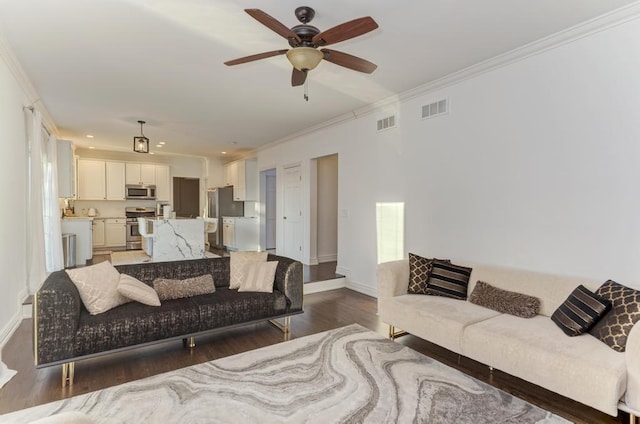 living room with visible vents, ornamental molding, baseboards, and wood finished floors