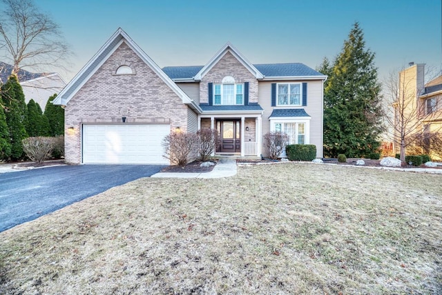 traditional home featuring a front lawn, brick siding, an attached garage, and driveway