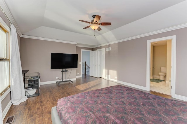 bedroom with a raised ceiling, wood finished floors, visible vents, and baseboards