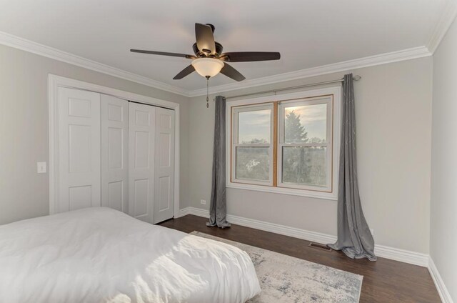 bedroom with crown molding, baseboards, dark wood finished floors, a closet, and a ceiling fan