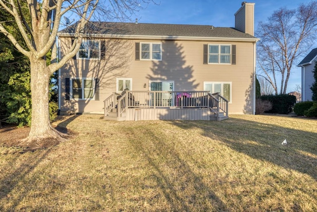 rear view of property with a yard, a deck, and a chimney