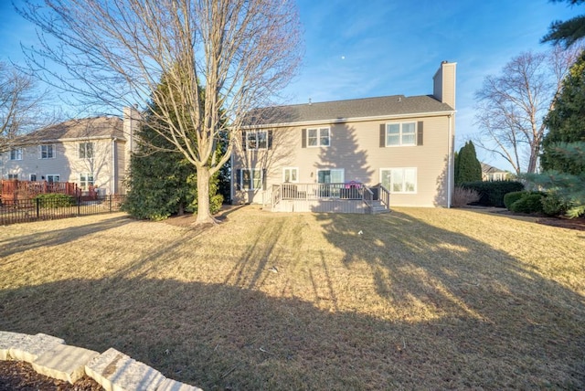 back of property featuring a lawn, a deck, a chimney, and fence