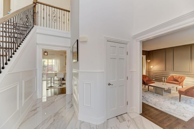 entrance foyer with a decorative wall, marble finish floor, stairway, and a towering ceiling