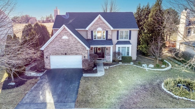 view of front of house with roof with shingles, an attached garage, a chimney, aphalt driveway, and brick siding