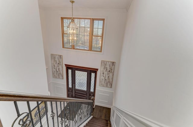 interior space with dark wood-type flooring, stairs, ornamental molding, an inviting chandelier, and a decorative wall