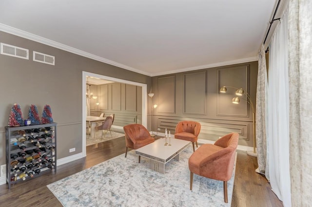 living area with visible vents, crown molding, a decorative wall, and dark wood-type flooring