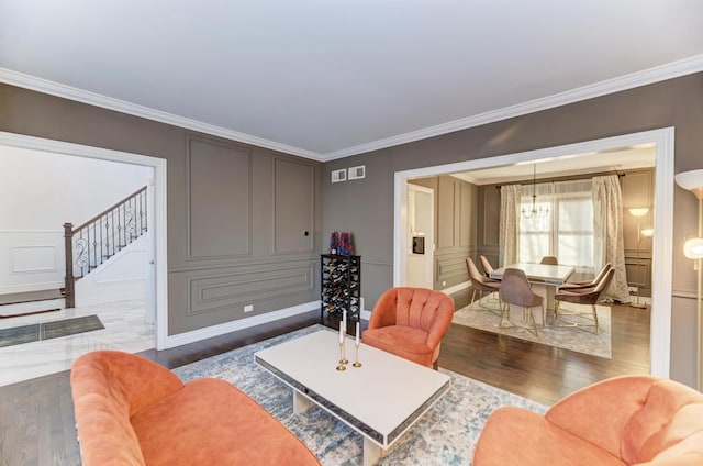 living area with crown molding, stairway, and a decorative wall