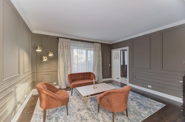 living room with wood finished floors, ornamental molding, and a decorative wall