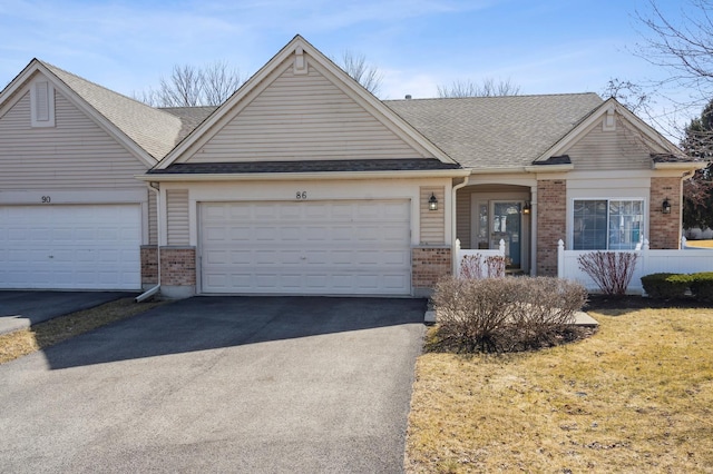 view of front of house with brick siding, driveway, a shingled roof, and a garage