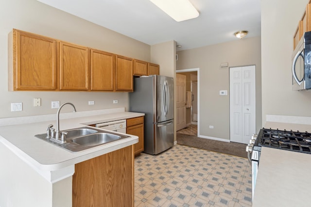 kitchen featuring light floors, a peninsula, a sink, stainless steel appliances, and light countertops