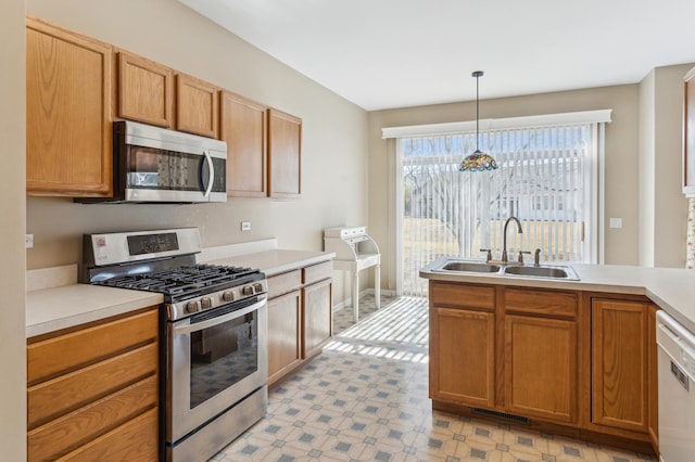 kitchen featuring decorative light fixtures, light floors, light countertops, appliances with stainless steel finishes, and a sink