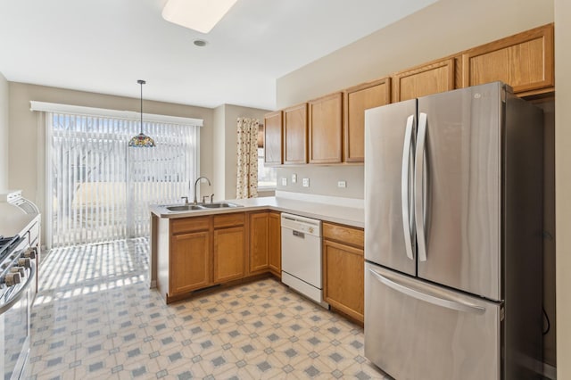 kitchen featuring a sink, appliances with stainless steel finishes, a peninsula, light countertops, and light floors