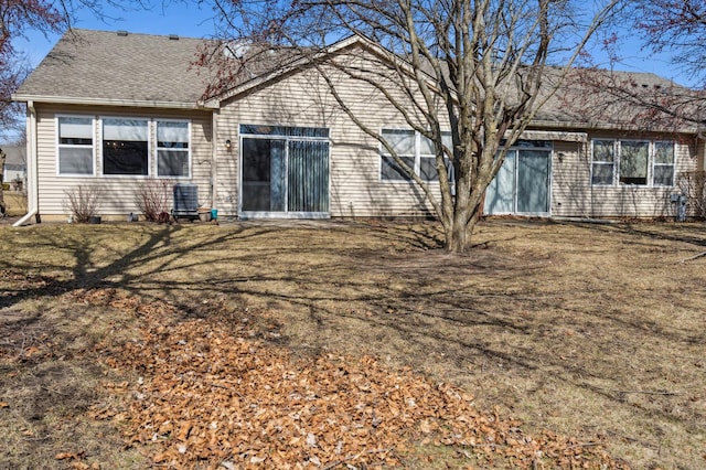 back of house with a yard and a shingled roof