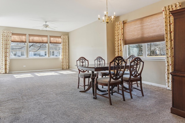 carpeted dining area with baseboards and ceiling fan with notable chandelier