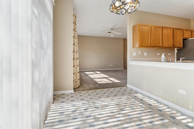 kitchen with a sink, baseboards, a ceiling fan, and light countertops