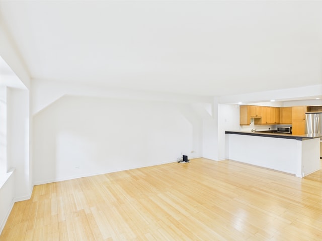 unfurnished living room with baseboards and light wood-type flooring