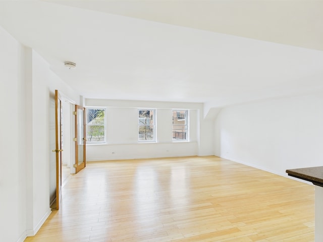 unfurnished living room with baseboards and light wood-style flooring