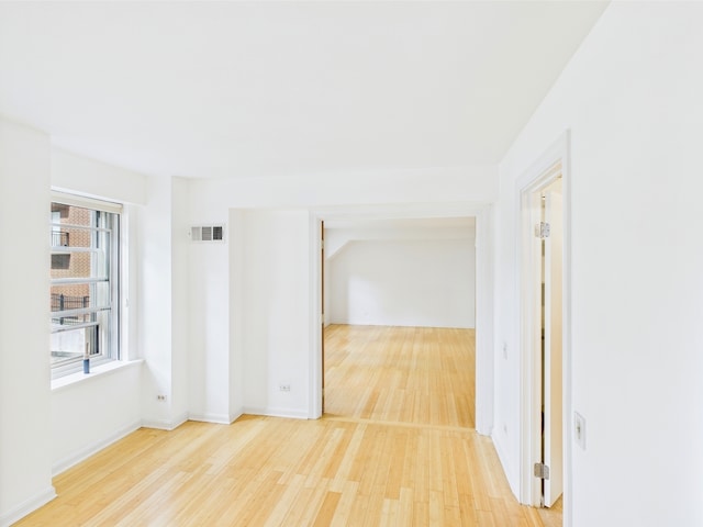 empty room with visible vents, baseboards, and wood finished floors