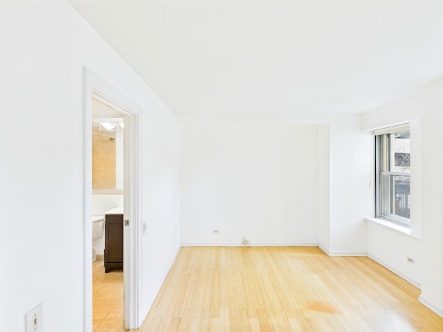 spare room with baseboards and light wood-type flooring