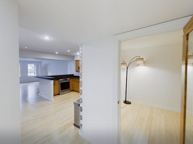 hallway with baseboards, recessed lighting, and light wood-style flooring