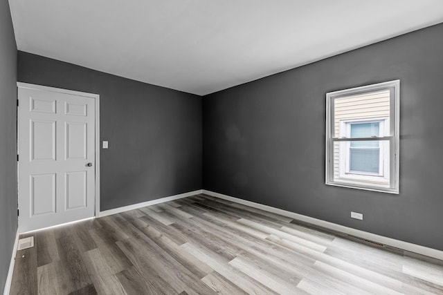 spare room with visible vents, baseboards, and wood finished floors