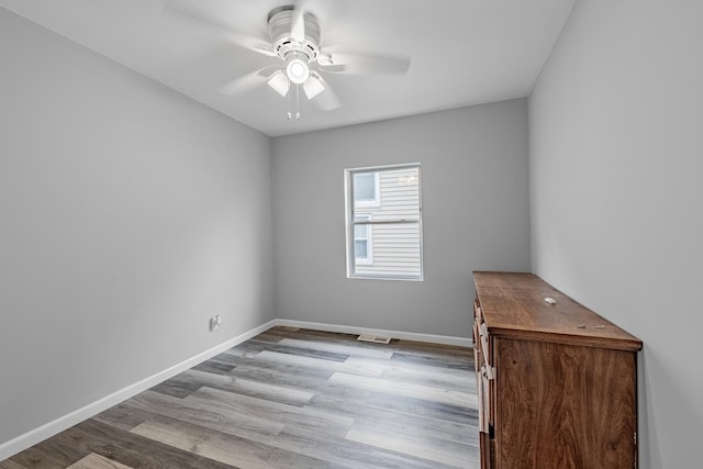 unfurnished room with ceiling fan, visible vents, baseboards, and wood finished floors