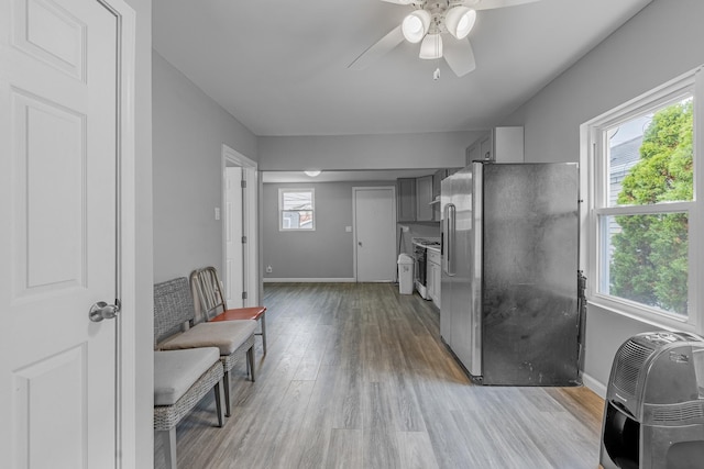 kitchen with heating unit, baseboards, light wood finished floors, gray cabinets, and stainless steel refrigerator with ice dispenser