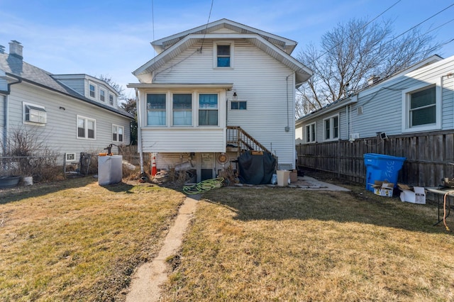 rear view of property with a lawn and fence