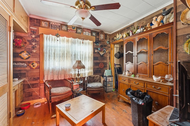 sitting room featuring ceiling fan, wood finished floors, and ornamental molding
